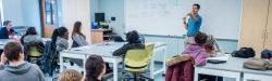 Faculty at whiteboard in front of room full of students