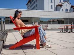 Student sitting in lounge chair outside on laptop.